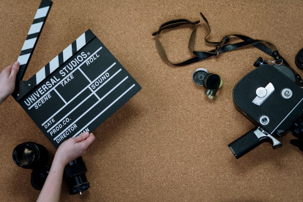 Film clapperboard, vintage camera and lenses laid out for video production