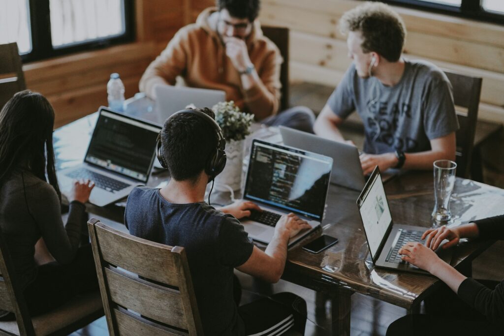 Creative team collaborating on laptops around a table in a studio
